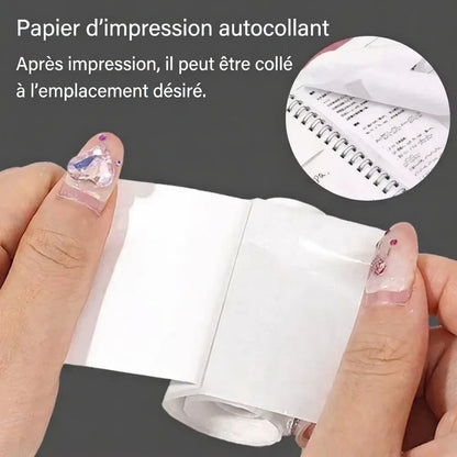 Gros plan mains tenant rouleau papier thermique autocollant pour imprimante photo enfant sans encre. Encadré : sticker photo collé sur cahier. Colle partout après impression – ludique et créatif 4-10 ans !